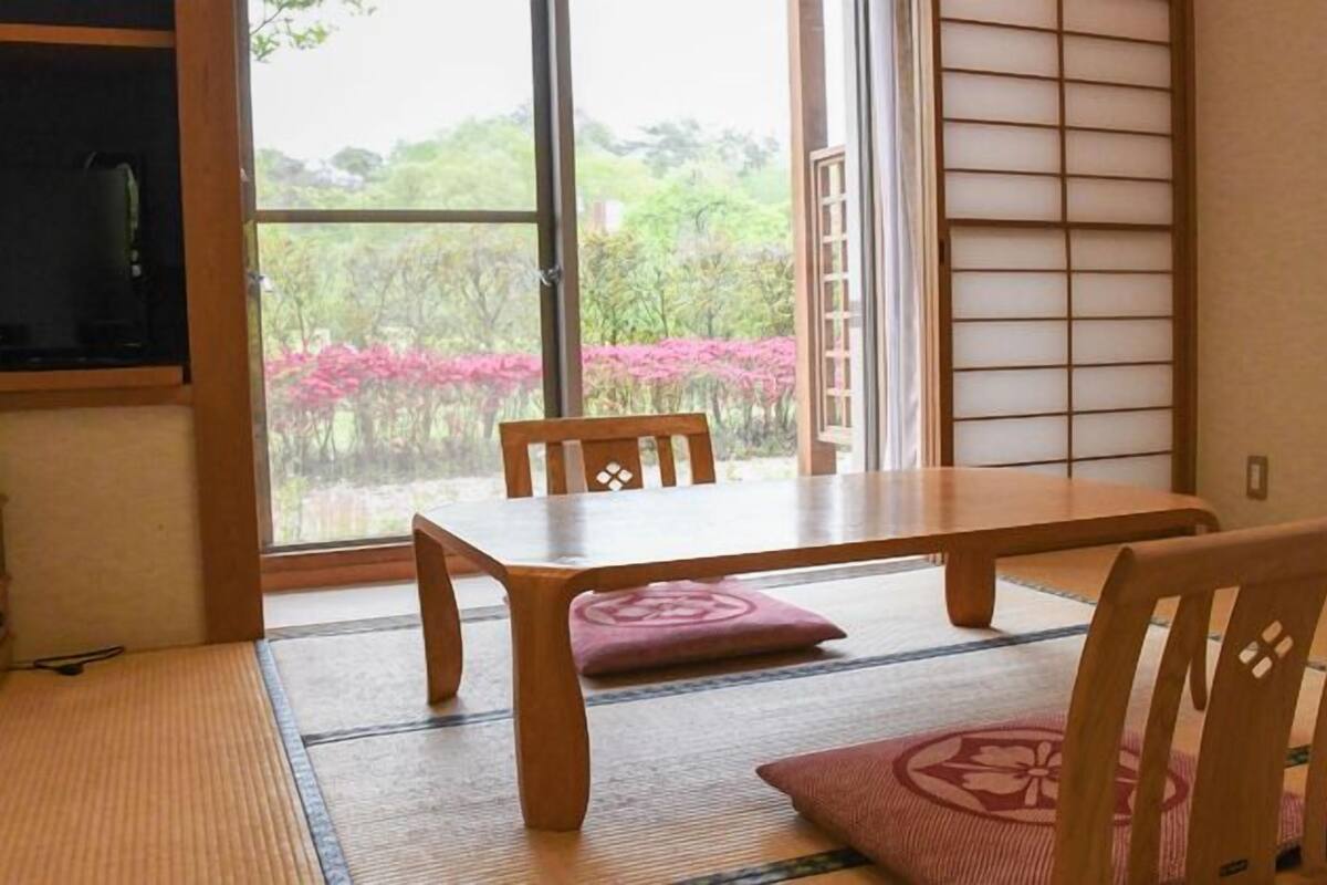 Um quarto japonês tradicional com tatames, uma mesa baixa e portas shoji.