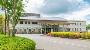 En modern byggnad med en överbyggd entré, omgiven av grönska och en klar himmel.