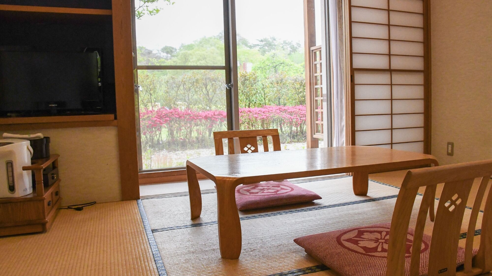 Una habitación japonesa tradicional con suelo de tatami, una mesa baja y puertas correderas shoji.
