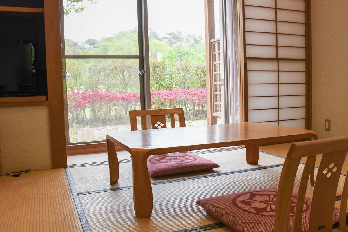 Um quarto japonês tradicional com tatames, uma mesa baixa e portas corrediças shoji.