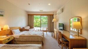 Ett hotellrum med två sängar, ett skrivbord, en stol, en TV och ett fönster med gardiner.