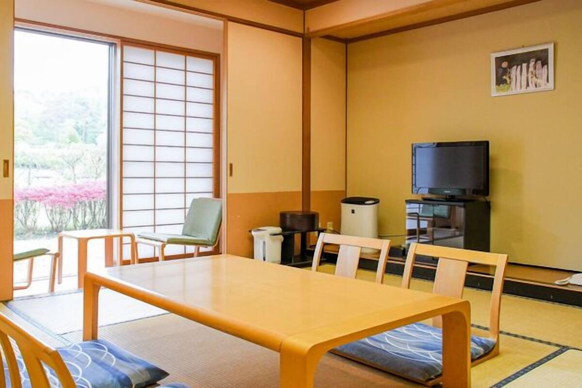 Perinteinen japanilaistyylinen huone, jossa on tatamimatto, matala pöytä ja televisio.