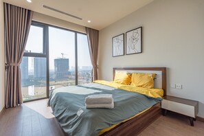 Een moderne hotelkamer met een groot bed, een nachtkastje en uitzicht op de stad door middel van ramen van vloer tot plafond.