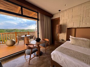 A hotel room with a balcony, a bed, a table with chairs, and a view of the landscape. - Hotel Mundo Maya Edzná (Tixmucuy)
