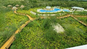 Ein Resort mit großem Pool, Holzstegen und üppiger Bepflanzung.