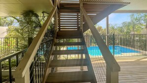 A wooden staircase leading to a covered deck with a pool. - Spacious 4-Bed Coastal Home with Water Views (Batehaven)