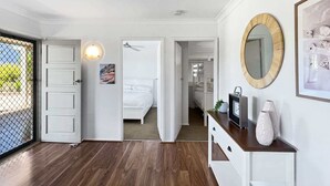 A room with a bed, a dresser, a mirror, and a picture on the wall. - Spacious 4-Bed Coastal Home with Water Views (Batehaven)