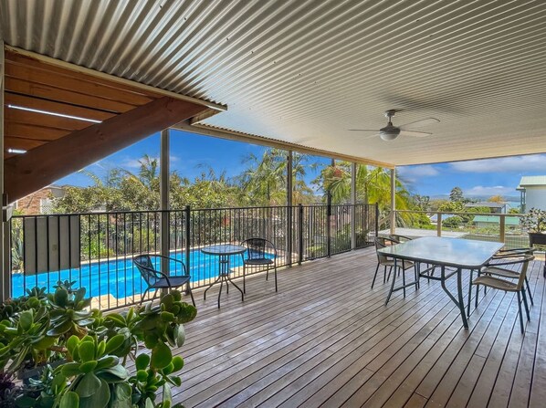A covered outdoor area with a pool, seating, and a view of the surrounding landscape.