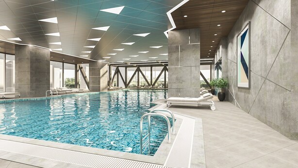 Ein modernes Hallenbad mit klarem Wasser, umgeben von großen Fenstern und Betonpfeilern.