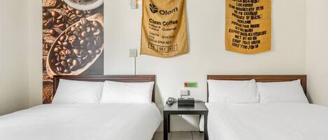 Quarto de hotel com duas camas, uma mesa de cabeceira e parede decorada com cartazes sobre café.