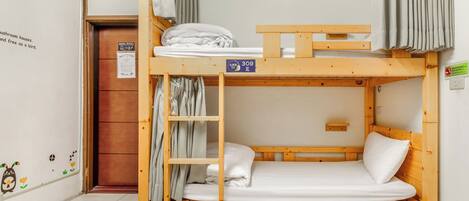 A bunk bed with a wooden frame and a mattress. There is a curtain on the upper bunk and a door with a sign on the lower bunk.