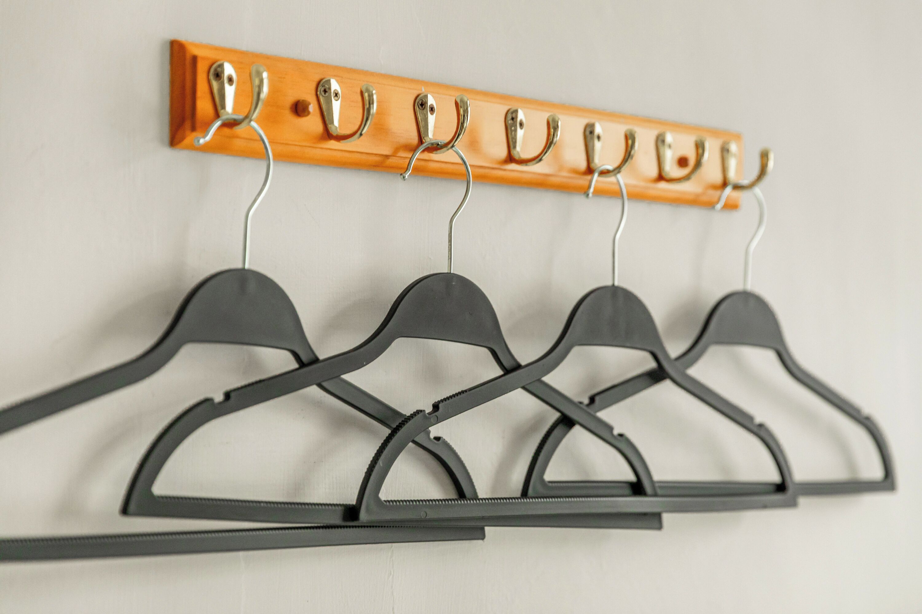 Een houten kapstok met zes haken en een set van vijf zwarte ophanghaakjes.