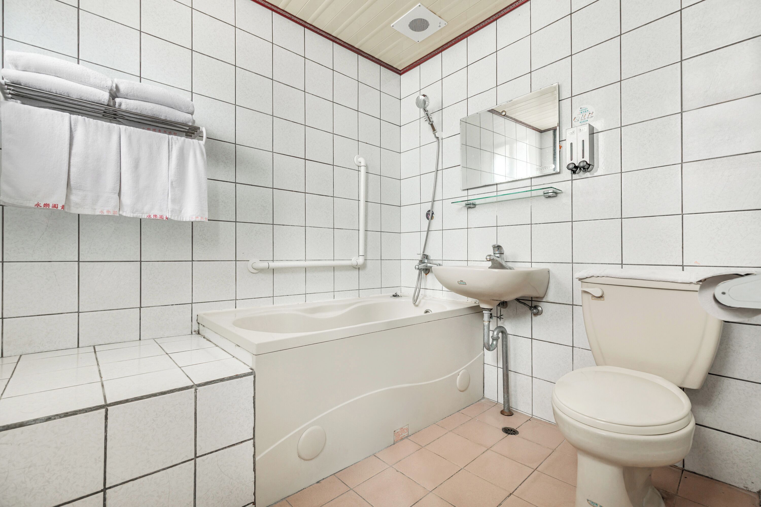 Un baño con azulejos blancos, una bañera, un lavabo y un inodoro.