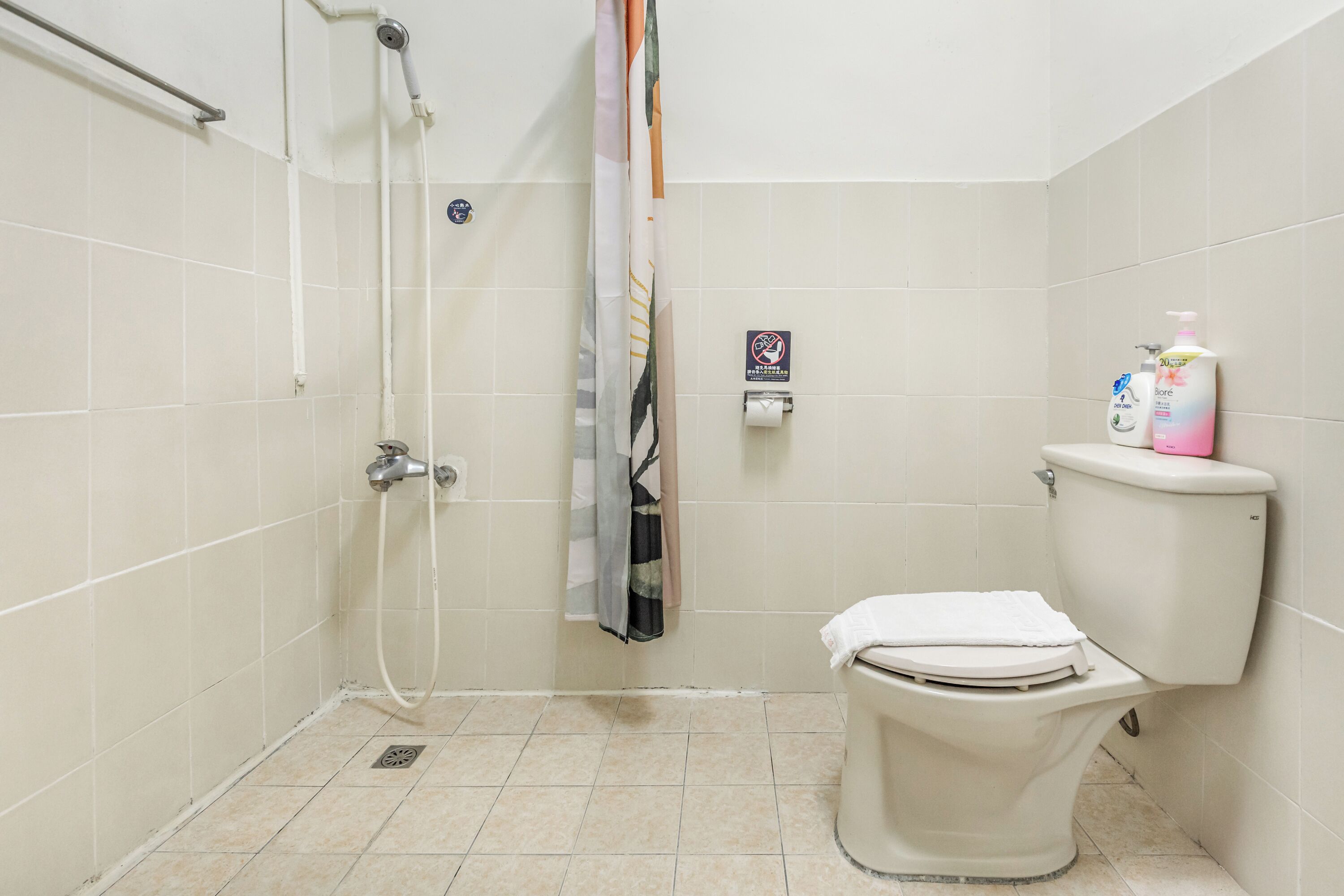 Un baño con ducha, inodoro y barra para toallas.
