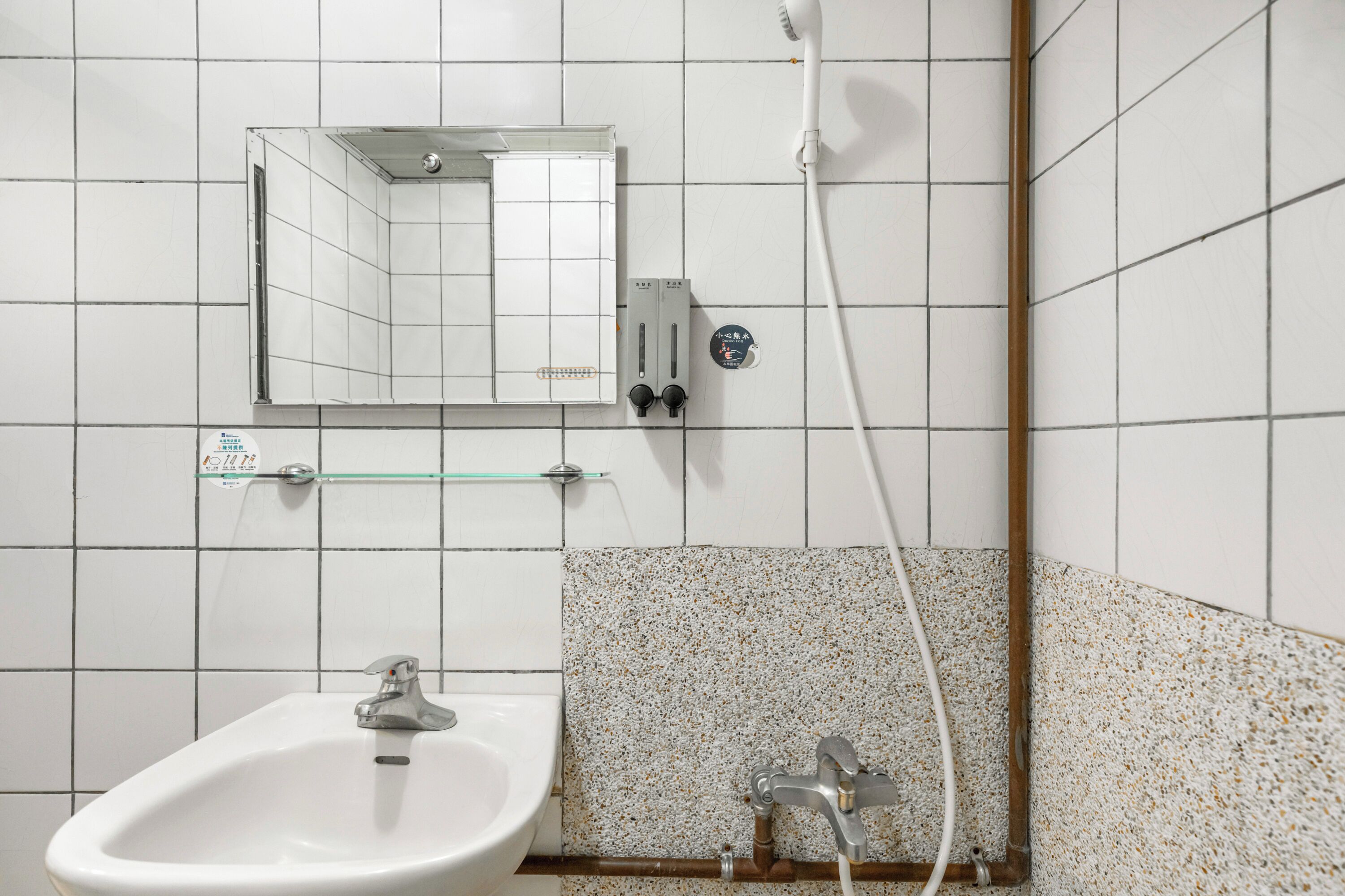 A bathroom with a sink, mirror, and shower.