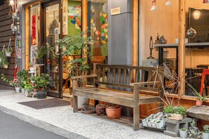 A wooden bench outside a shop with various potted plants and a small table nearby. - Forever happiness hostel  (Puli)