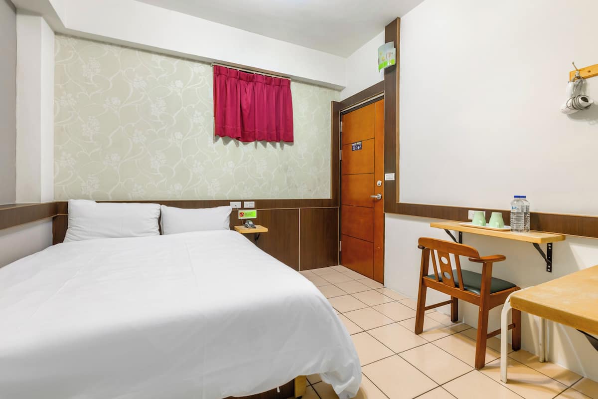 Ein Hotelzimmer mit Bett, Schreibtisch, Stuhl, Kleiderschrank und Badezimmer.