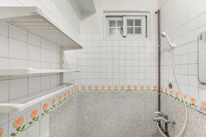 A bathroom with white tiled walls, a window, a shower with a handheld showerhead, and a corner shelf. - Forever happiness hostel  (Puli)