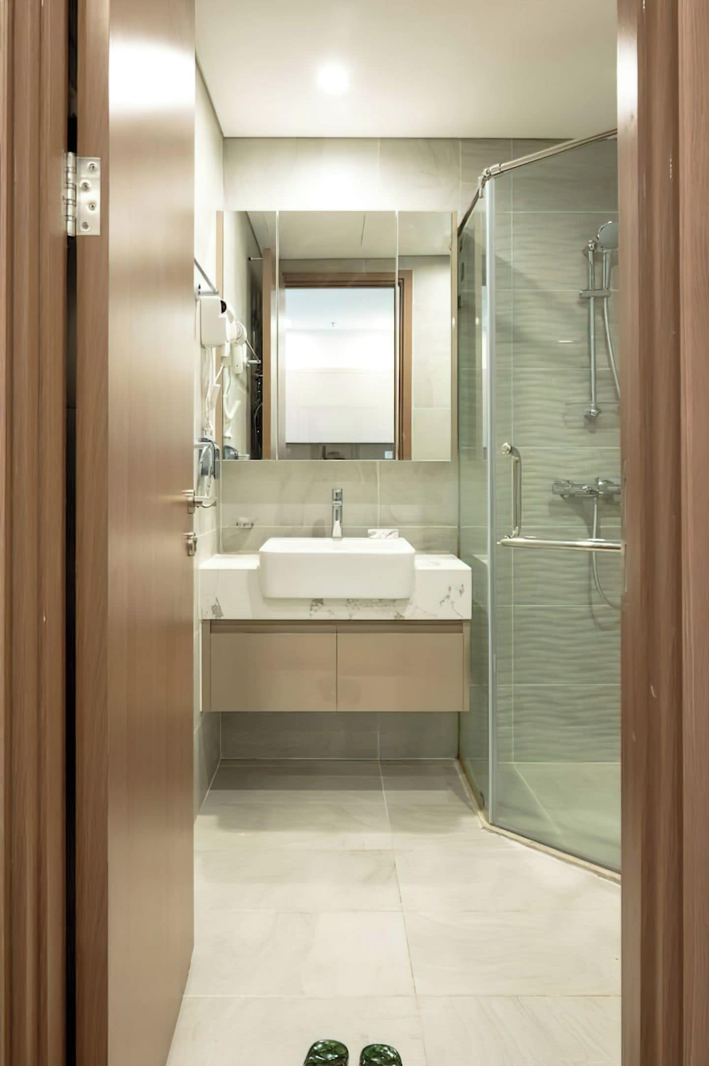 A modern bathroom with a glass shower enclosure, a white sink, and a mirror above it.