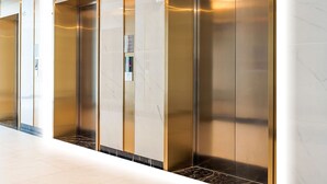 A modern elevator with metallic doors and a marble wall. - The Zenpark Tower - Vinhomes Ocean Park (Hanoi)