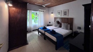 A bedroom with two beds, a wooden ceiling, a window with curtains, and a nightstand with a lamp. - castaway lodge (Pointe Au Sel)