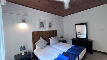 A double bed with a wooden headboard, two bedside tables with lamps, a ceiling fan, and a mirror.
