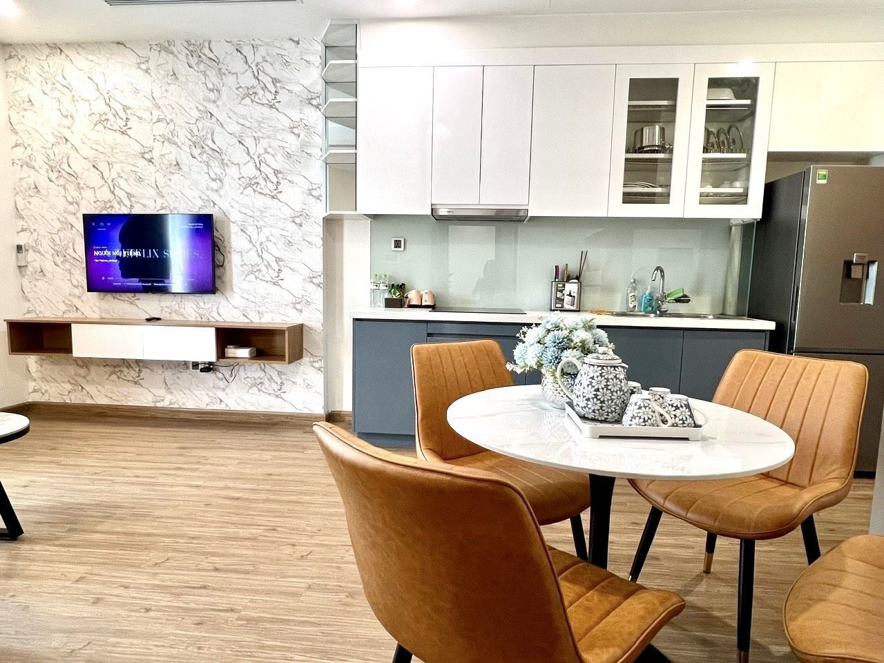 A modern kitchen with white cabinets, a built-in oven, and a stainless steel refrigerator.