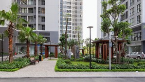 A modern urban plaza with a bench, palm trees, and a small gazebo. - Vinhomes Green Bay Apartments (Hanoi)