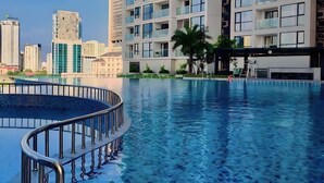 A modern residential building with a swimming pool, featuring balconies and a clear view of the city skyline. - Vinhomes Skylake by Emily in Town (Hanoi)
