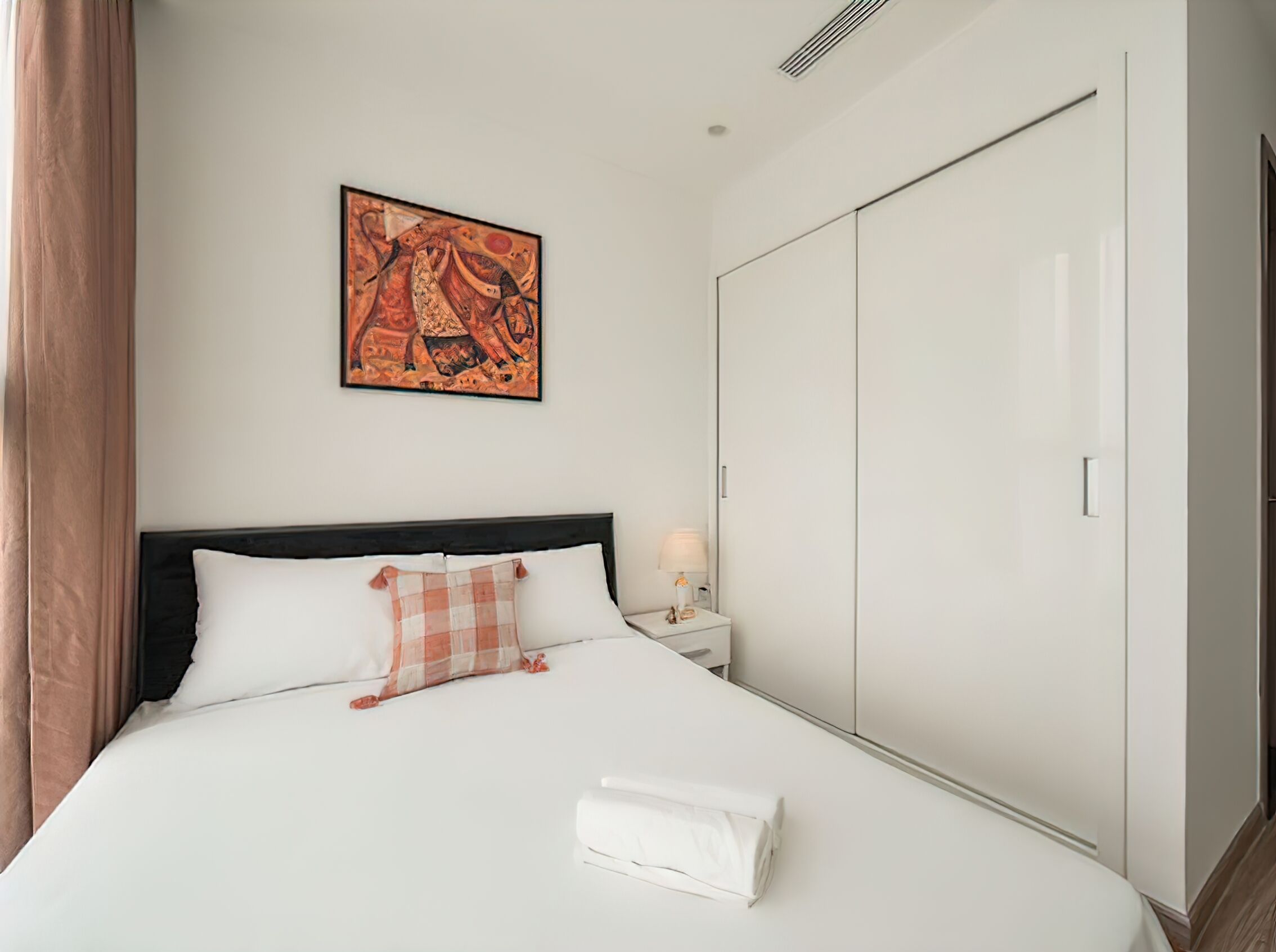 Une chambre d’hôtel avec un lit, une table de chevet, une armoire et un tableau au mur.