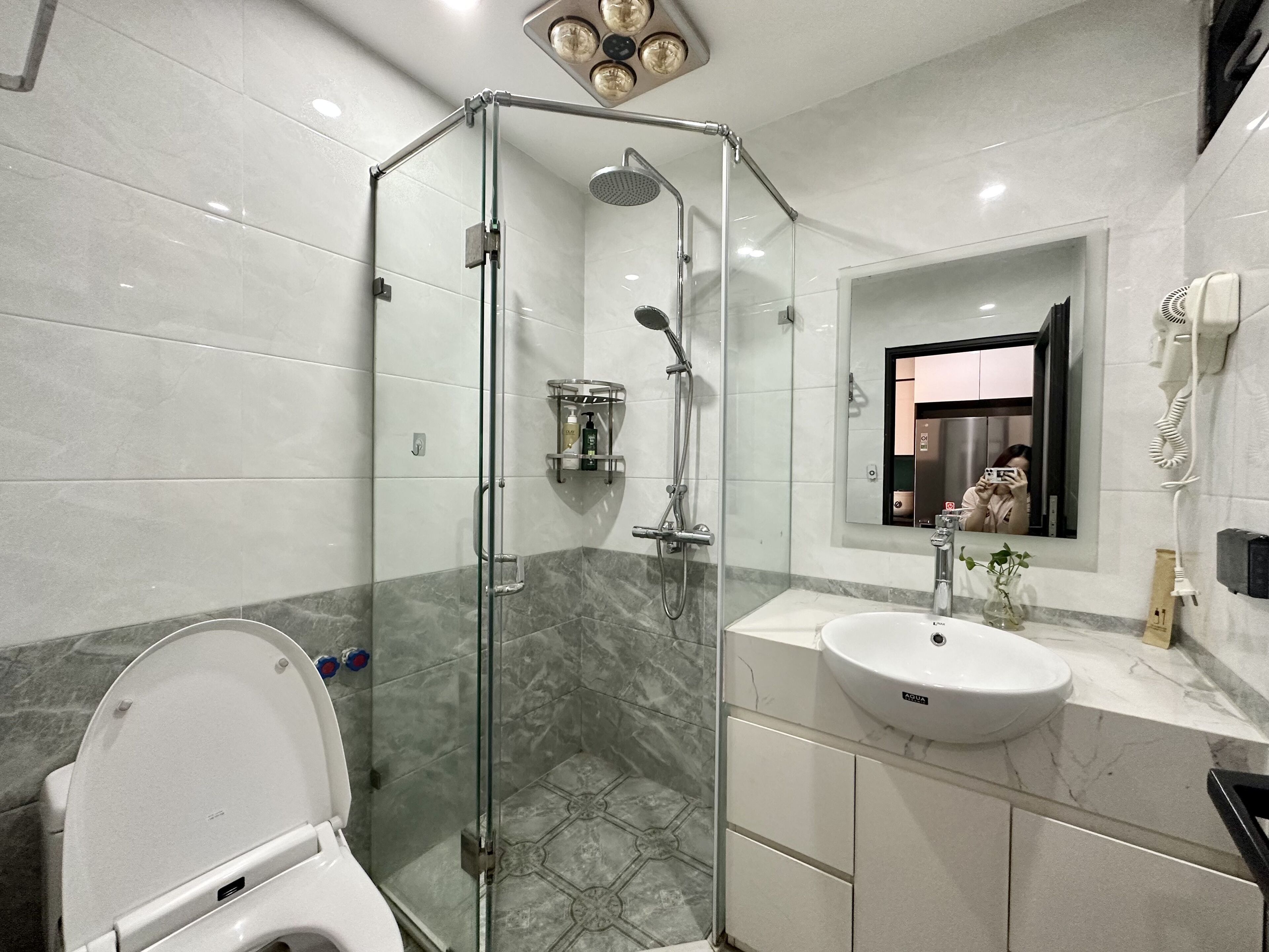 A modern bathroom with a glass-enclosed shower, a white sink, and a toilet.