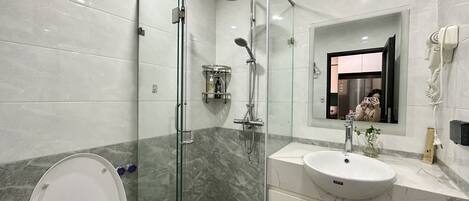 A modern bathroom with a glass-enclosed shower, a white sink, and a toilet.