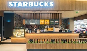 Een Starbucks winkel met een houten toonbank, menuborden en een vitrine met gebak.