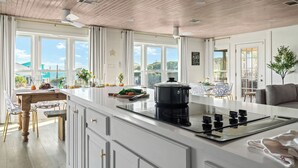 A modern kitchen with a large island, white cabinetry, and a view of the outdoors. - Private Pool 20Steps2Beach Arcade Ping Pong Sleeps18 Barrel Sauna  (Gulf Shores)