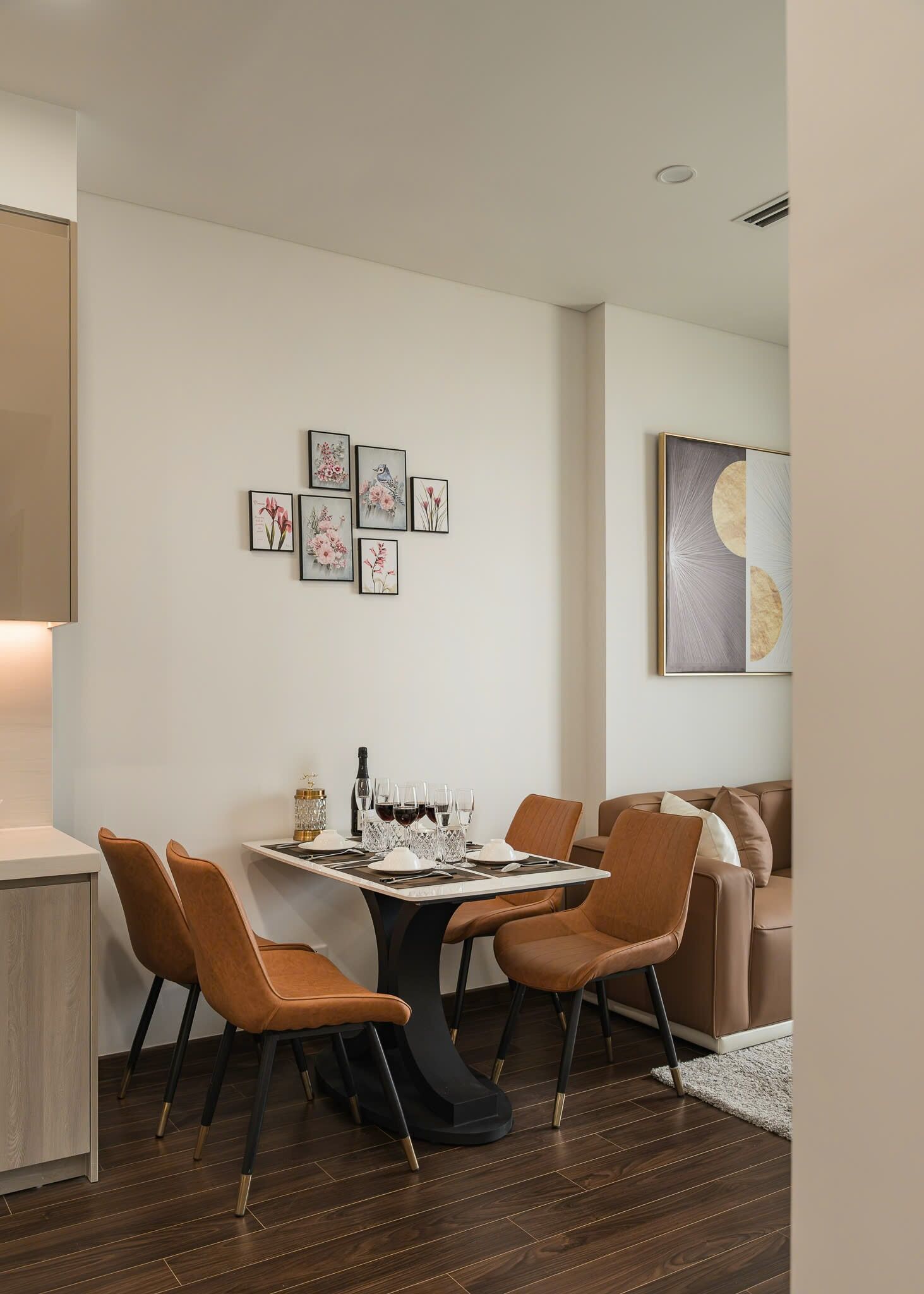 A modern dining area with a table set for four, surrounded by brown leather chairs.