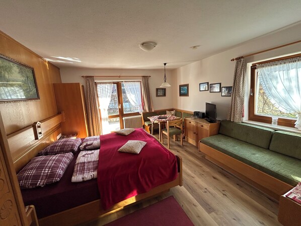Une pièce confortable avec un lit, un bureau et un canapé vert.