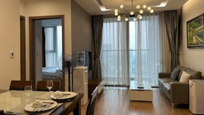 Ein modernes Wohnzimmer mit einer Couch, einem Esstisch gedeckt mit Tellern und Gläsern, einem Wasserspender und einem Deckenventilator.