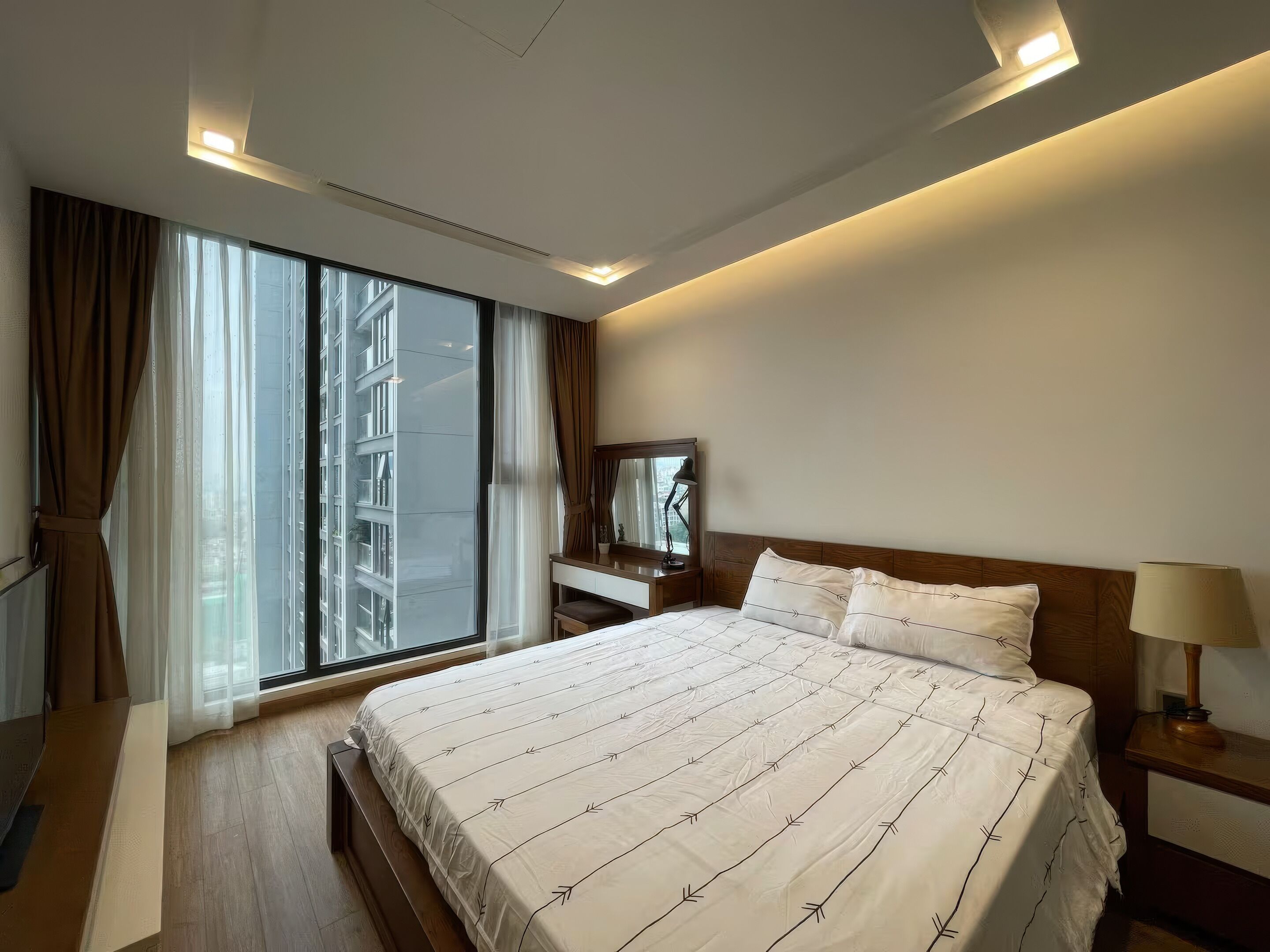 Una camera d'albergo moderna con un letto grande, un comodino, una scrivania e una finestra con tende.