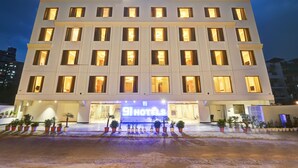 Un hôtel reconnaissable à son grand panneau « 9 Hotels », à ses nombreux étages et à son entrée bien éclairée.