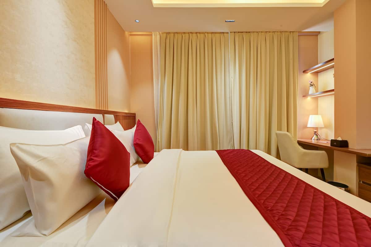 Een hotelkamer met een groot bed, een bureau, een stoel en een lamp.