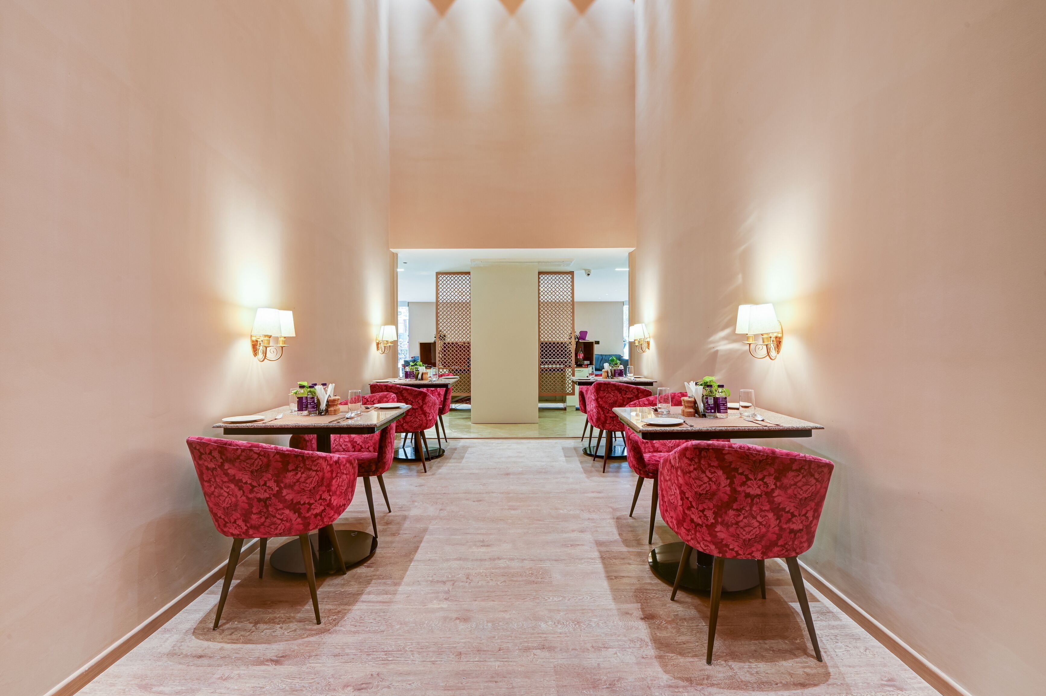 A restaurant with tables and chairs arranged in a central aisle, with light fixtures on the walls.