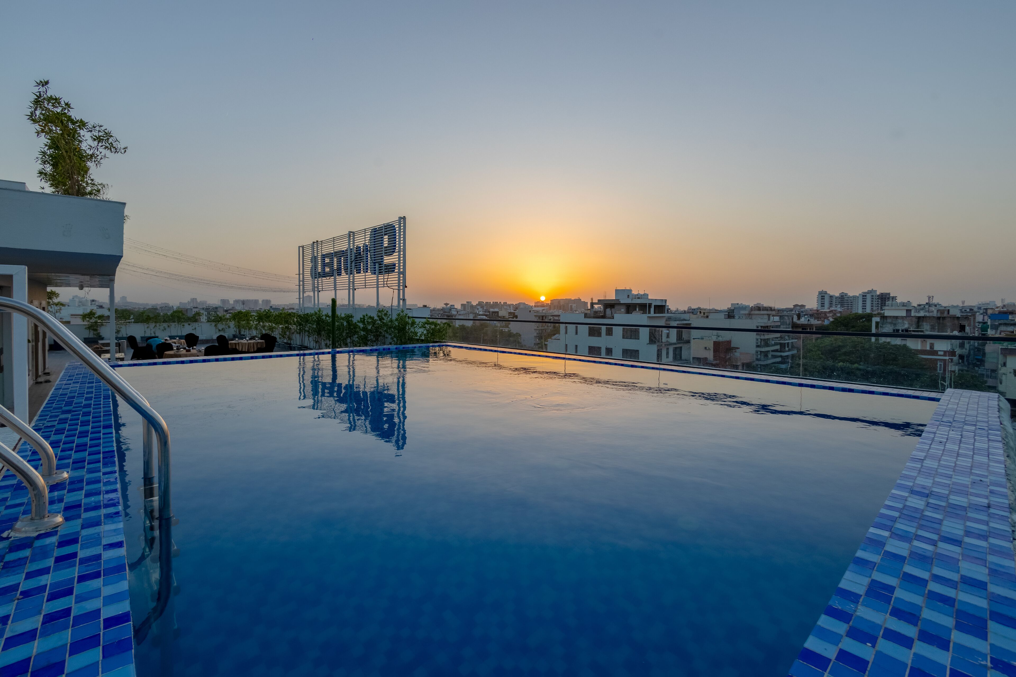 Una piscina en la azotea con vistas despejadas al atardecer, rodeada de edificios.