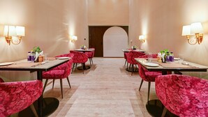 Un espace repas avec des tables et des chaises, une arche centrale et des luminaires fixés au mur.