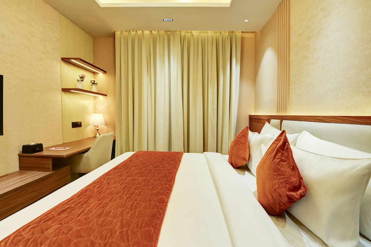Een hotelkamer met een bed, een bureau, een lamp en een raam met gordijnen.