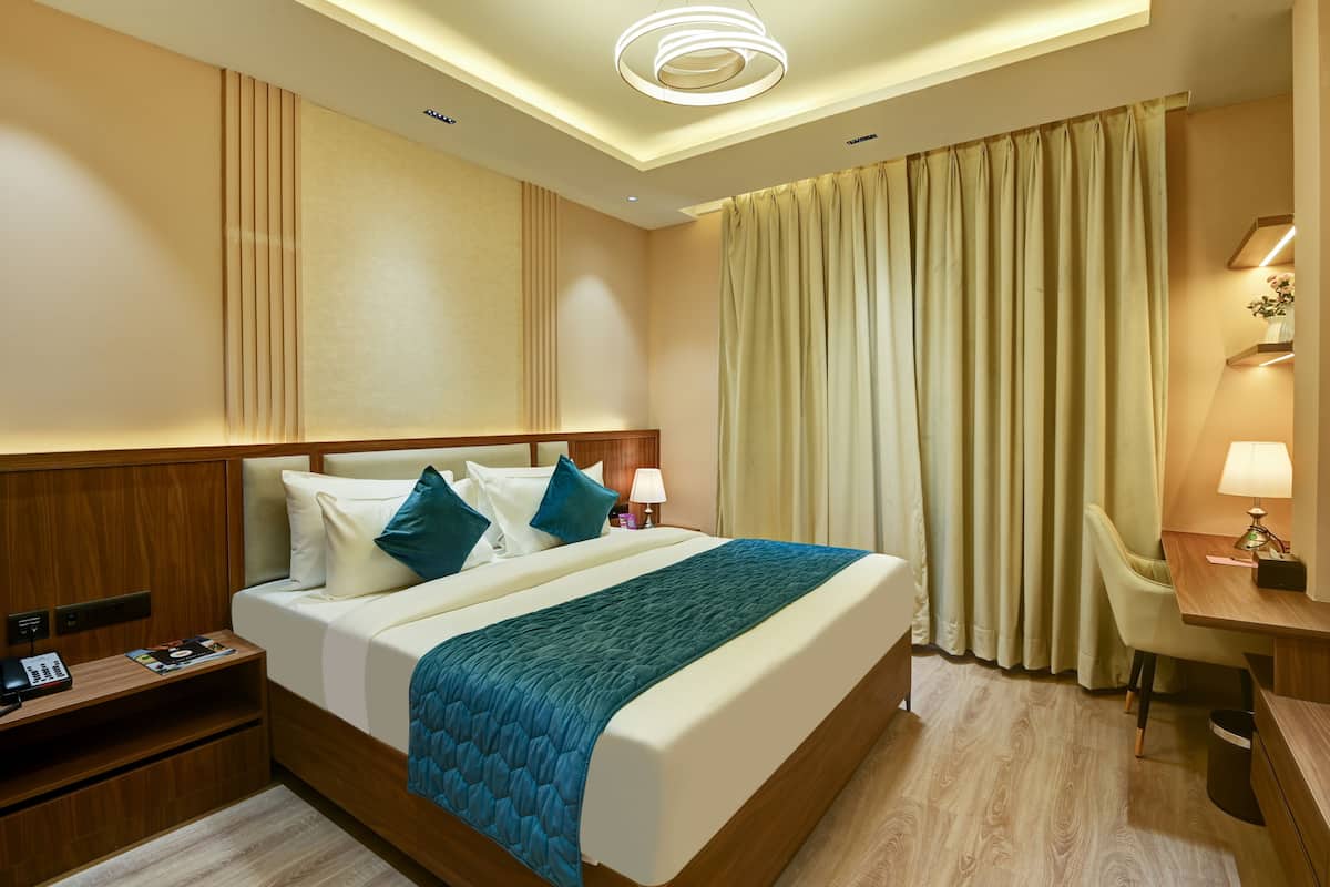 Een hotelkamer met een groot bed, een bureau, een stoel, een nachtkastje en een lamp.