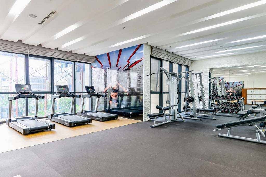 A gym with treadmills, weight machines, and a large mirror.