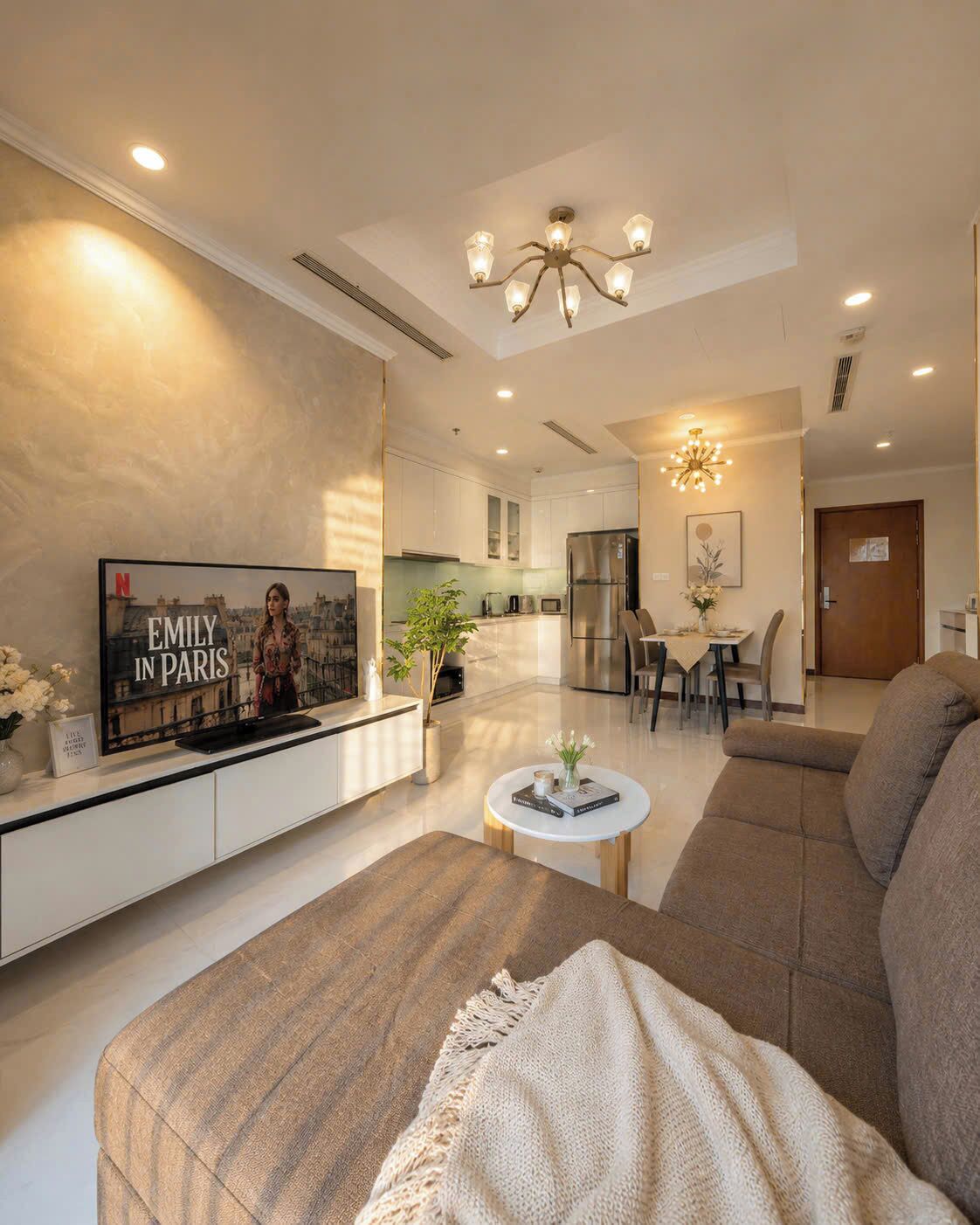 A modern living room with a sofa, a coffee table, a TV, and a dining area with chairs and a table.