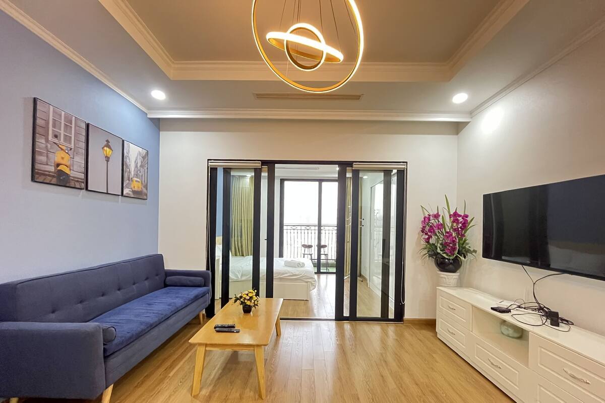 A modern living room with a blue sofa, a wooden coffee table, and a flat-screen TV on a white cabinet.