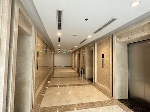 A modern hallway with marble flooring, recessed lighting, and elevators. - Vinhomes Royal City by Emily in Town (Hanoi)
