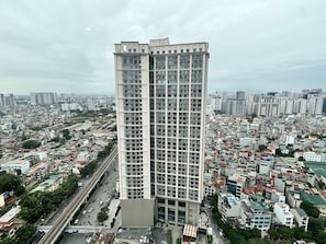 A high-rise building with a modern architectural design, surrounded by a densely populated urban area with various buildings and streets. - Vinhomes Royal City by Emily in Town (Hanoi)